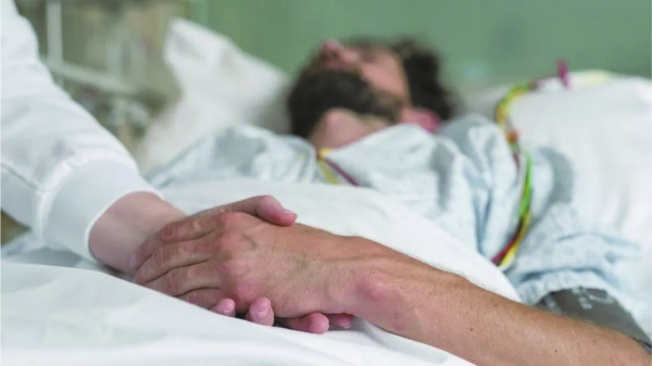 ▲ A doctor holds a patient’s hand, providing support in assisted dying / BBC